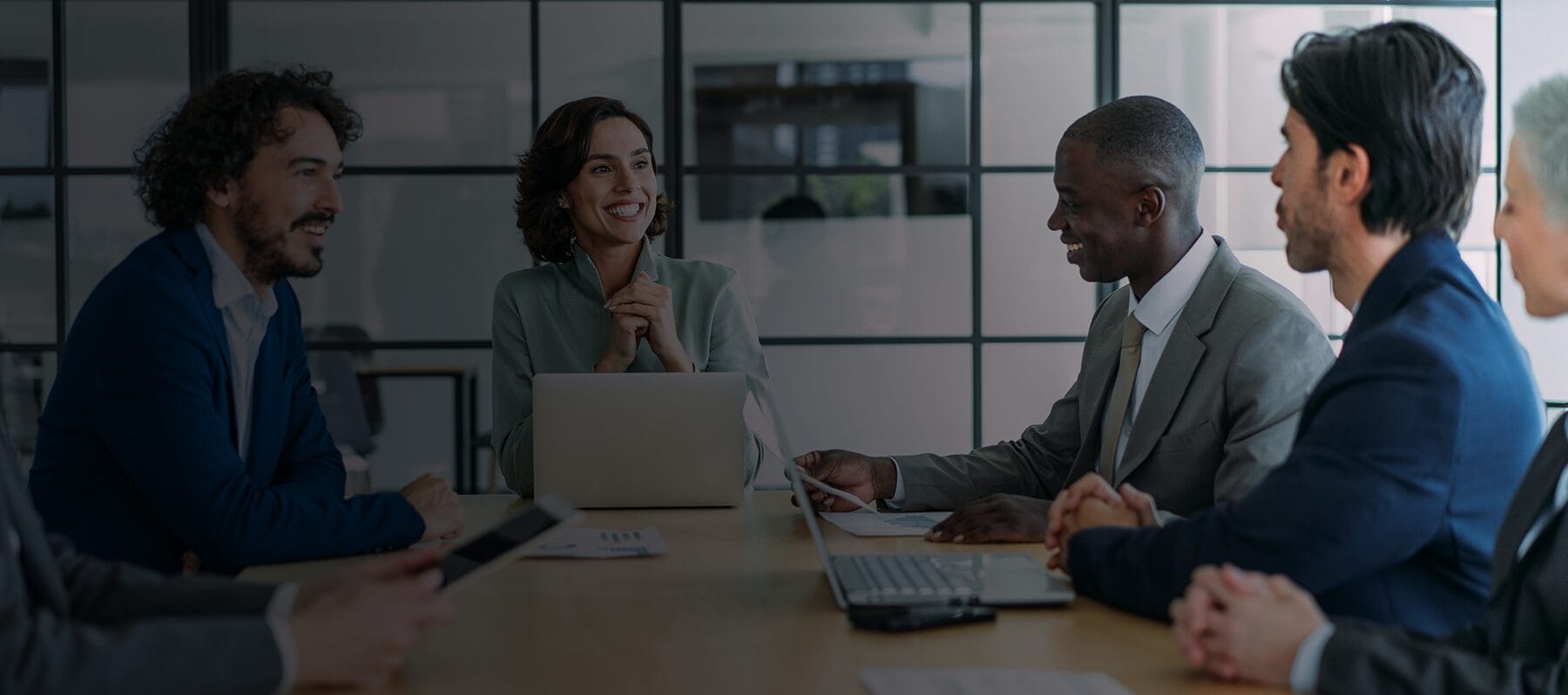 Business professionals in a meeting discussing artificial intelligence strategies for business, with laptops open and a collaborative atmosphere.