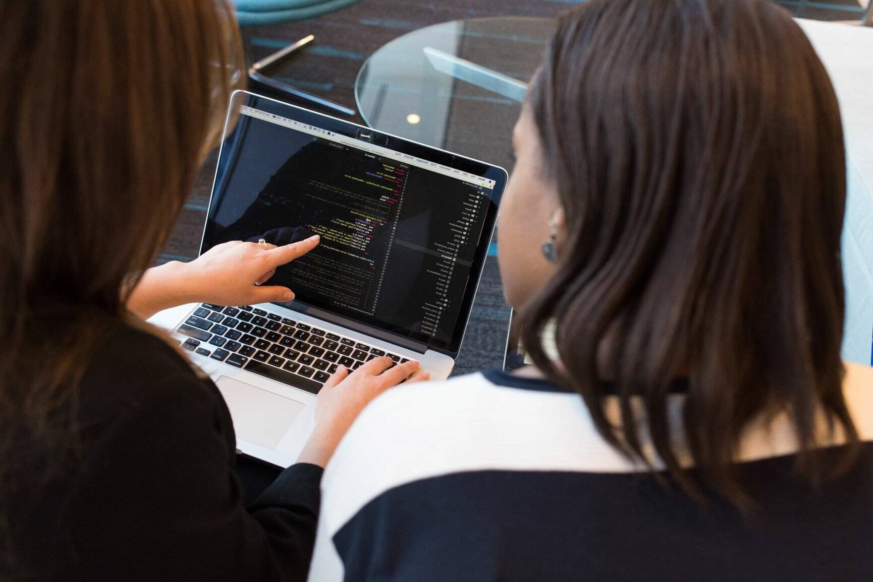 IT professional teaching code to a student on a laptop.