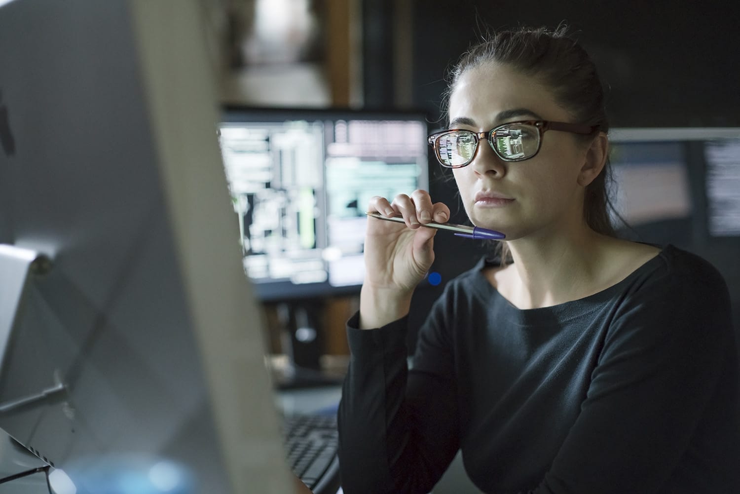 Woman Information systems specialist brainstorming and analyzing data on a laptop in a data center.