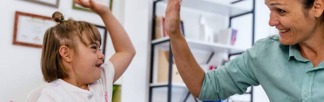 Special education teacher giving a high five to a young student, celebrating progress and learning.
