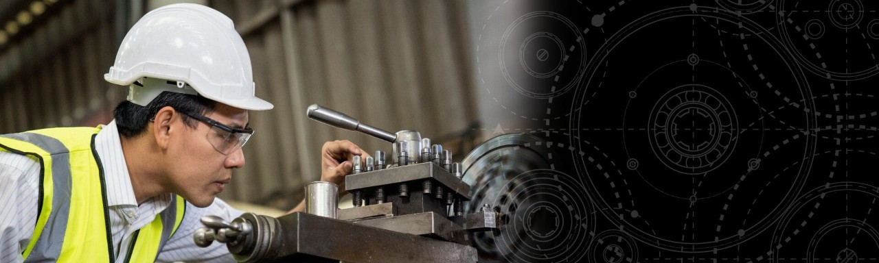 Mechanical engineer wearing a safety helmet and high-visibility vest inspecting machinery in a manufacturing facility.