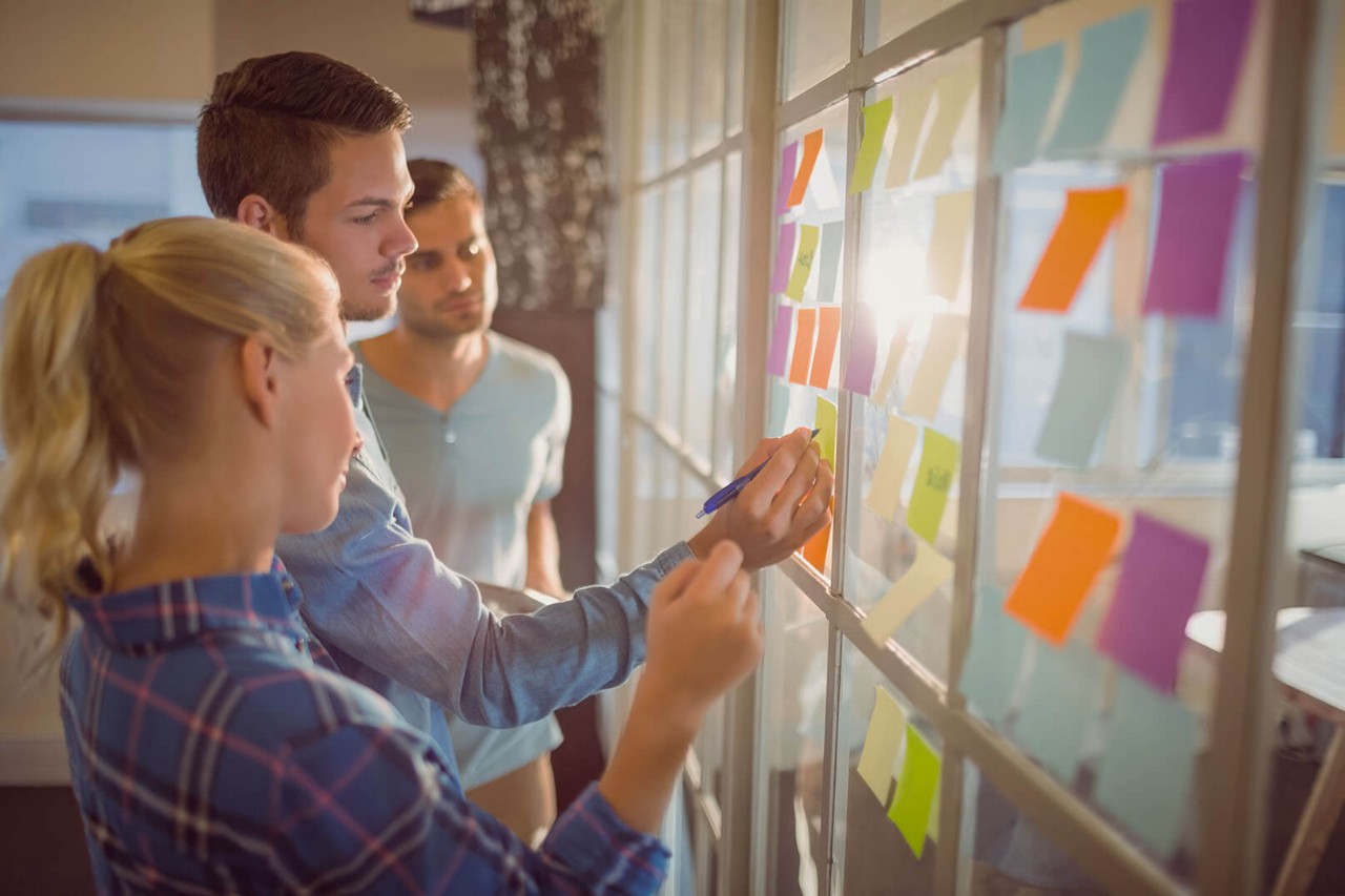 Communication associate degree students studying with note cards on windows.